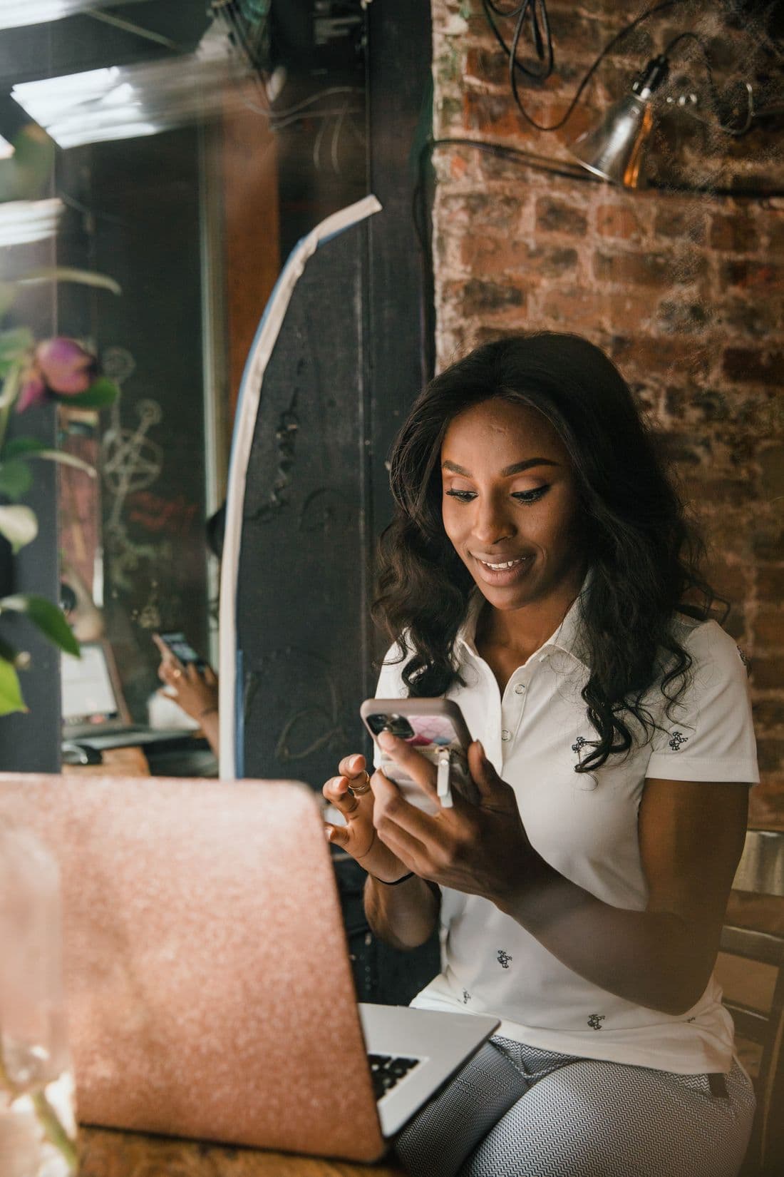 Une gérante derrière son bar lit une notification sur son téléphone en souriant